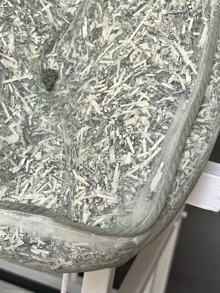 detail view of transparent mattress stuffed with shredded paper currency