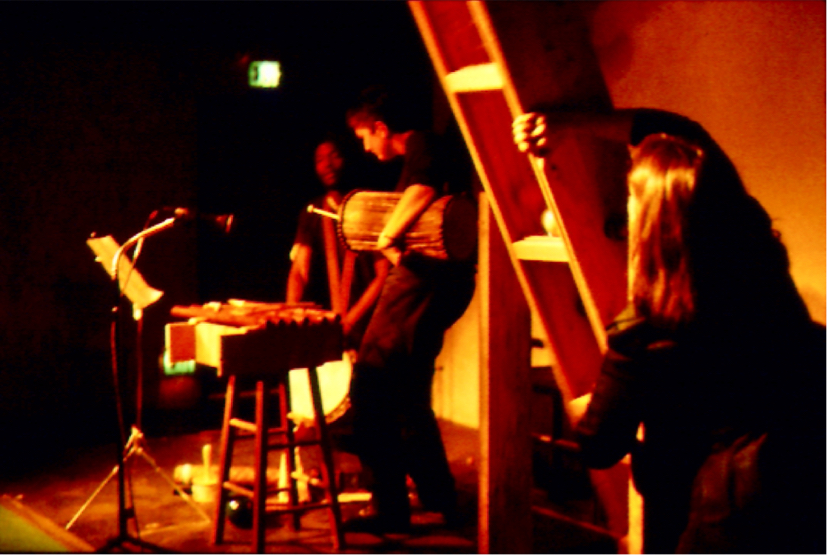 Judith plays the wood sound column in the foreground, other performers are in the distance