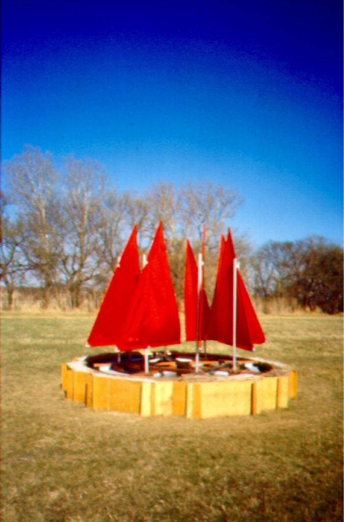 Installation situated in a dry grassy field with bare winter trees.