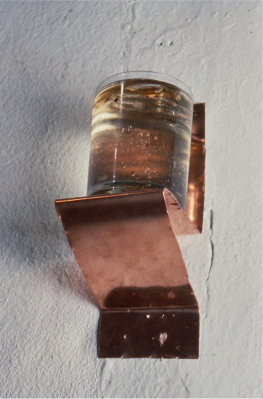 Candle sconce: wick floats in oil and water in a tumbler on copper sheet.