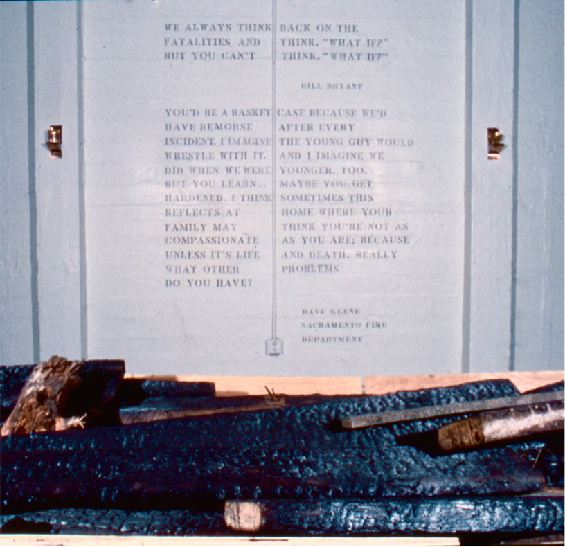 Closeup of trough filled with burnt lumber with wall text in the background.