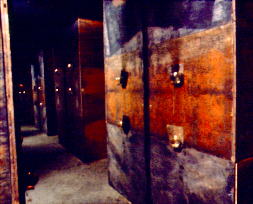 Interior of x-shaped room of burnt plywood, with endless reflection in opposing candlelit mirrors.