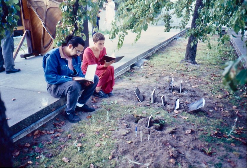 A man and a woman sit on the walkway and read unearthed journals.