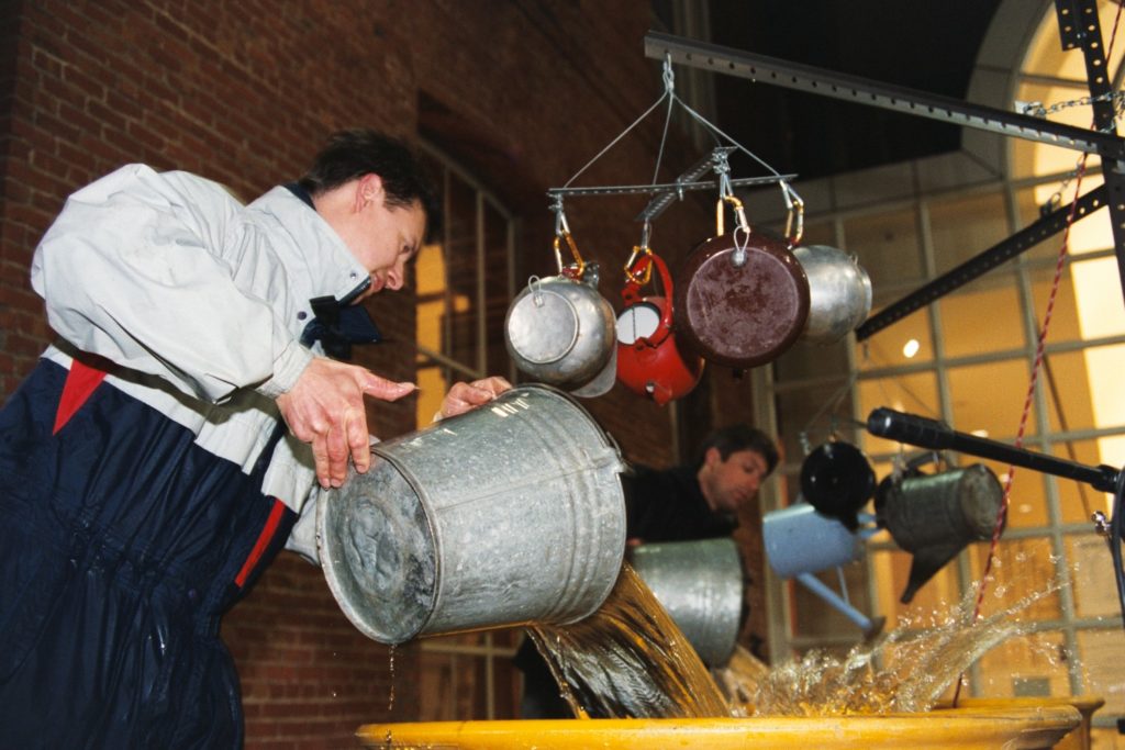 Brian pours water from a metal bucket