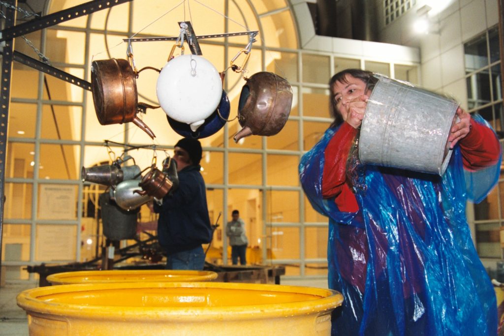 Judith holds metal bucket ready to pour