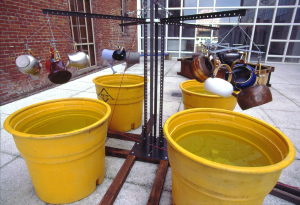 tea kettles raised above four large water buckets