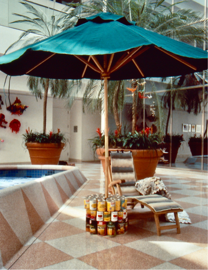 The chaise sits "poolside" next to a fountain inside an atrium dotted with potted palm trees.