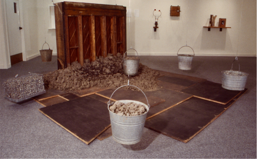Piano carcass on scattered plywood, suspended objects filled with gravel - 4 buckets & 1 cage.