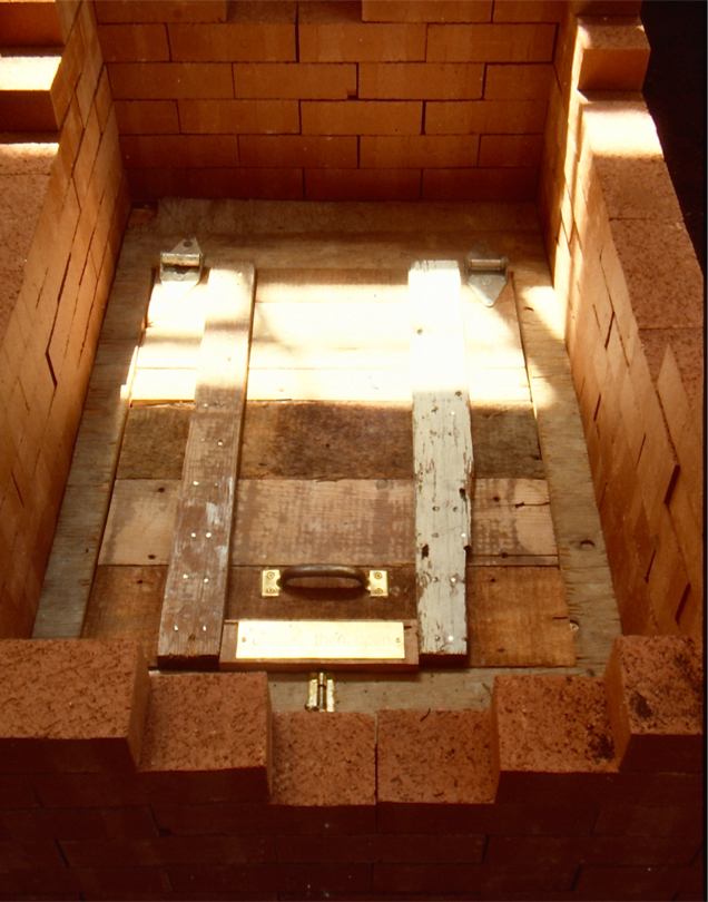 Detail: trap door made of rough reused wood inside brick well.